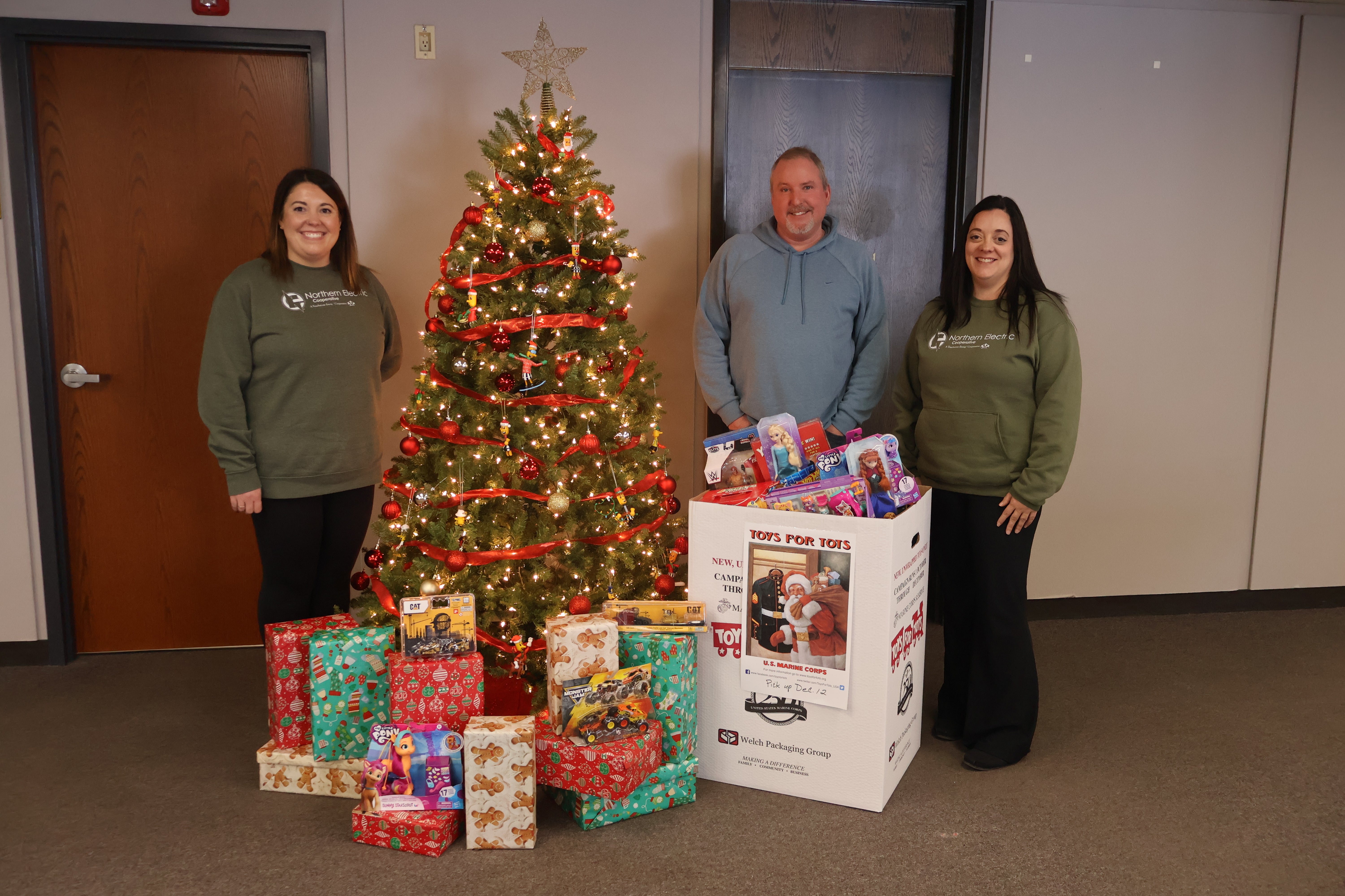 NEC employees Derek, Rene, and Christy stand with the toys collected and given to Toys for Tots.