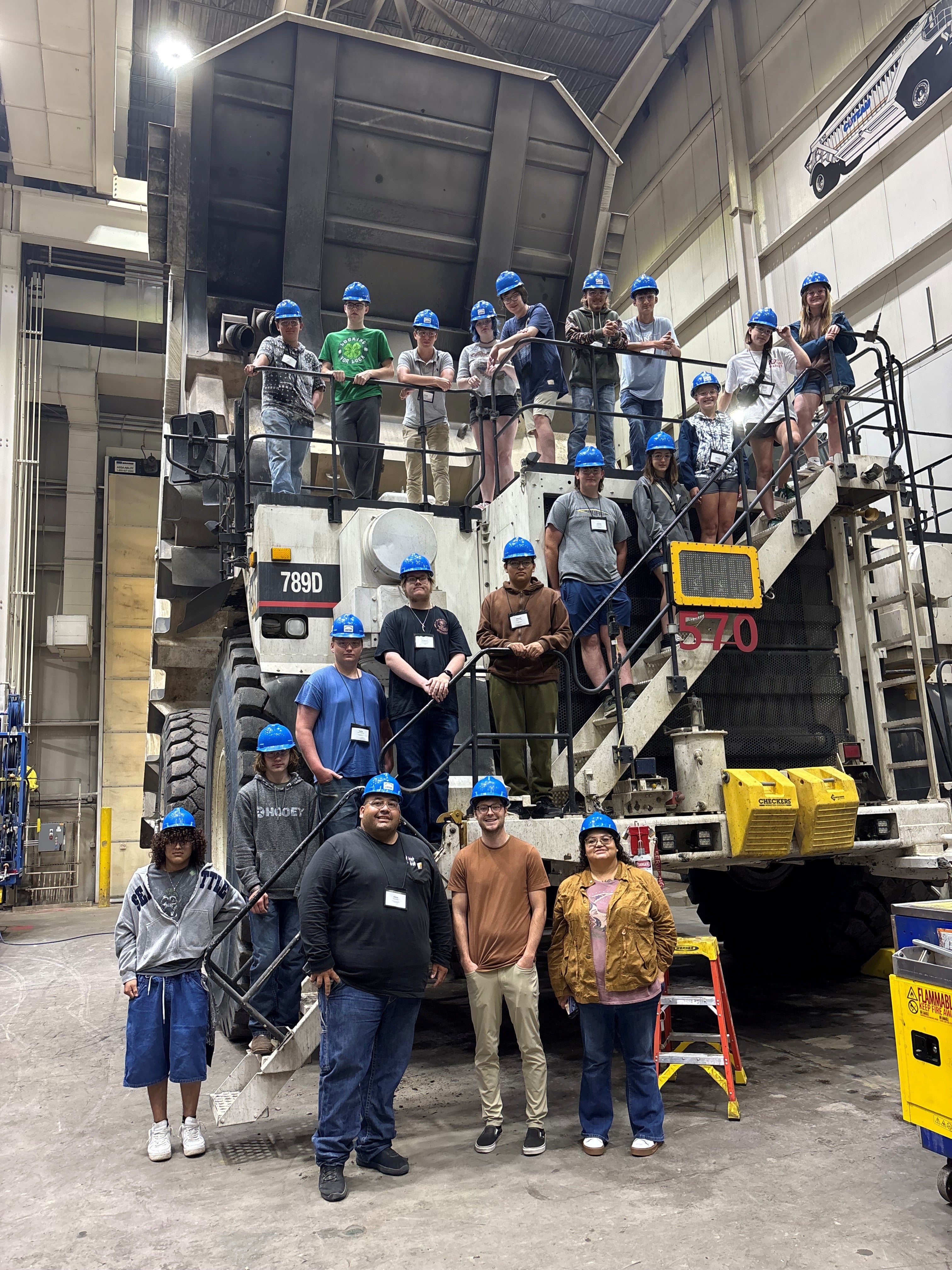 Students stand in front of a massive truck used in the mine